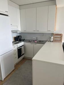 een keuken met witte kasten, een wastafel en een fornuis bij Modern and Cozy apartment with Sauna2 in Espoo