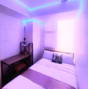 2BR in Azure - Beach in the City with WiFi في مانيلا: غرفة نوم مع سرير ومكتب مع أضواء
