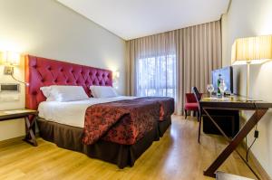 Una habitación de hotel con una cama grande y un escritorio. en Exe Guadalete, en Jerez de la Frontera