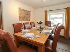 uma sala de jantar com uma mesa de madeira e cadeiras de couro em Fenns Barn em Leek