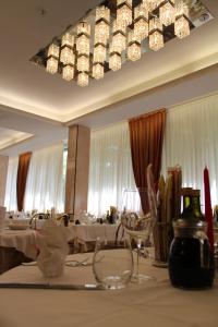 a dining room with tables and a large chandelier at Hotel de Paris in Lido di Savio