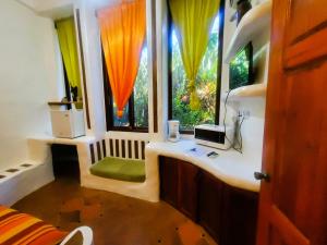 Habitación con escritorio y 2 ventanas con cortinas. en Reef View Pavilions - Villas & Condos en Lance aux Épines