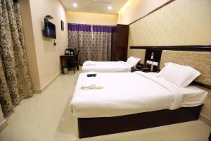 a hotel room with two beds and a television at Hotel Sitara Grand Ramchandrapuram in Hyderabad