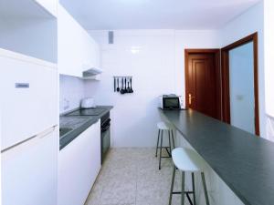 uma cozinha branca com um balcão e dois bancos em Live Candelaria Alsaca con Balcón y Vista al Mar em Candelaria