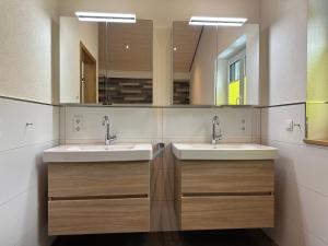 a bathroom with two sinks and two mirrors at Traumferienhaus Leimbach am Nürburgring in Leimbach