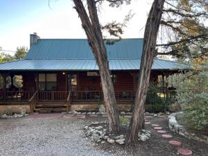 Lake Whitney Log Cabin في Lakewood Harbor: كابينة خشب فيها بلكونه و شجرتين