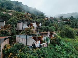 ein Paar steht auf dem Balkon eines Hauses auf einem Hügel in der Unterkunft ฮิมสวนโฮมสเตย์ 