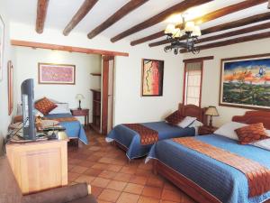 a room with three beds and a television in it at Hotel Villa Cristina in Villa de Leyva