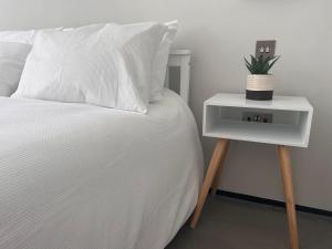 a white bed with a nightstand with a plant on it at Modern Apartment Central Woodstock with Parking in Woodstock