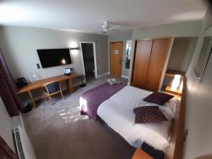 a bedroom with a bed and a desk and a television at Roffey Park Institute in Horsham