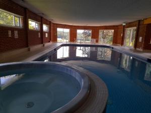 a large swimming pool with a tub in a room at Roffey Park Institute in Horsham