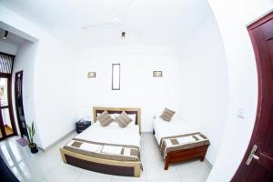 ein weißes Zimmer mit 2 Betten und einem Tisch in der Unterkunft Hotel Blue Bird in Negombo