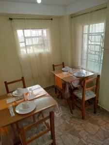 a dining room with two tables and chairs and two windows at Pousada la colline in Santo Antônio do Pinhal