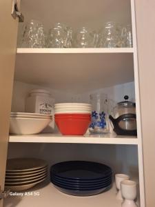 a cupboard filled with plates and bowls and dishes at City Apartment Kirkkokatu 10, ilmainen kadunvarsipysäköinti in Kuopio
