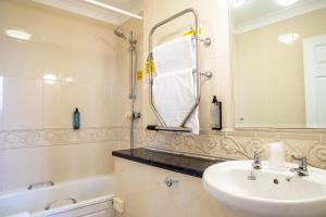 a bathroom with a sink and a mirror and a tub at Arnos Manor Hotel in Bristol