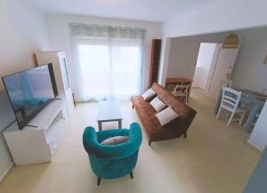 sala de estar con TV, sofá y sillas en Adosado cerca de la playa, en Gran Alacant