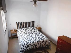 a bedroom with a bed with a black and white comforter at Adosado cerca de la playa in Gran Alacant