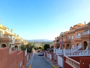 una calle de la ciudad con edificios y un coche en la carretera en Adosado cerca de la playa, en Gran Alacant