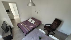- une chambre avec un lit, une chaise et une télévision dans l'établissement La maison dans le jardin, à Viry-Châtillon