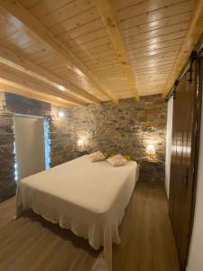a bedroom with a bed in a room with a stone wall at Casa do Tear in Sobreira Formosa