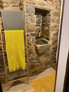 a bathroom with a yellow towel and a stone wall at Casa do Tear in Sobreira Formosa