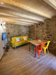 ein Wohnzimmer mit einem Tisch und einem gelben Sofa in der Unterkunft Casa do Tear in Sobreira Formosa