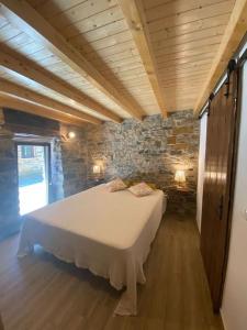 ein Schlafzimmer mit einem großen Bett in einer Steinmauer in der Unterkunft Casa do Tear in Sobreira Formosa
