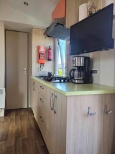 a kitchen with a counter with a stove and a microwave at Location Mobil home 4/6 personnes camping avec piscine 1,5km de la plage Saint-Pair-sur-Mer en Basse Normandie (Sud manche) 35km du Mont saint-Michel in Saint-Pair-sur-Mer