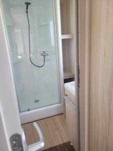 een badkamer met een douche en een glazen deur bij Location Mobil home 4/6 personnes camping avec piscine 1,5km de la plage Saint-Pair-sur-Mer en Basse Normandie (Sud manche) 35km du Mont saint-Michel in Saint-Pair-sur-Mer