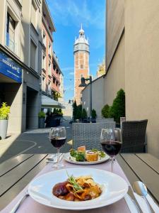 a table with two plates of food and two glasses of wine at Golden Tulip Krakow Kazimierz in Kraków
