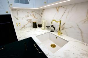 a bathroom with a sink and a gold faucet at Apartament BOTANIQ #free parking in Bydgoszcz +8 photos