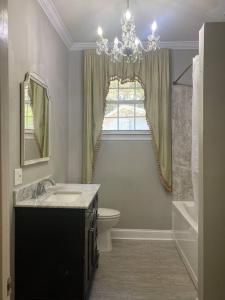 a bathroom with a sink and a toilet and a chandelier at Quiet & Beautiful Country Home in Baker