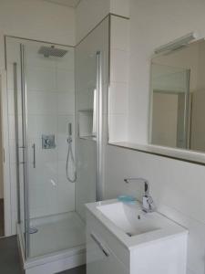 baño blanco con ducha y lavamanos en Moderne 2 Zimmerwohnung/ Eggenstein/nähe KIT Nord, en Eggenstein-Leopoldshafen