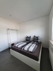 1 dormitorio con 1 cama con almohadas blancas y negras en Moderne 2 Zimmerwohnung/ Eggenstein/nähe KIT Nord, en Eggenstein-Leopoldshafen