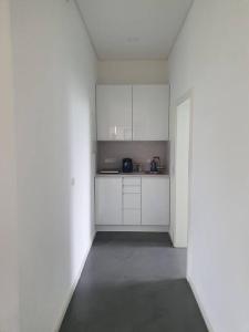 una cocina blanca con armarios blancos y puerta en Moderne 2 Zimmerwohnung/ Eggenstein/nähe KIT Nord, en Eggenstein-Leopoldshafen