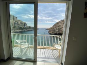 a room with a balcony with a view of the ocean at Best Of Xlendi SeaFront Apartments in Xlendi