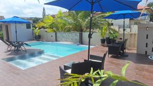 een zwembad met blauwe parasols en stoelen naast bij KoKo Palm Inn in Accra