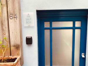Una puerta azul con un cartel al lado de una planta en The Salt Box, en Dartmouth