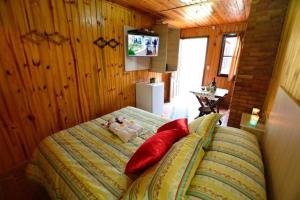 um quarto com uma cama com almofadas vermelhas e uma televisão em Pousada Aconchego em Monte Verde