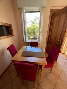 a dining room table with red chairs and a window at La Casa dei Sogni in Intra