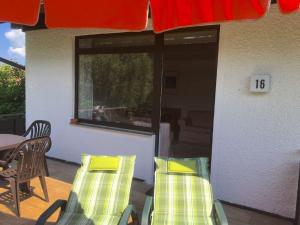 eine Terrasse mit 2 Stühlen, einem Tisch und einer Nummer in der Unterkunft Feriendorf Reichenbach - Wieselweg 16 in Nesselwang