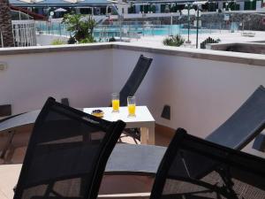 dos vasos de zumo de naranja sentados en una mesa en un balcón en Appartamento Maspalomas Vista Golf con piscina, en Maspalomas