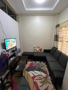 een woonkamer met een zwarte bank en een tv bij 2-Storey Rental Unit w/ Garage in Balanga Bataan in Tinajero