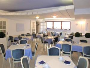 ヴュルツブルクにあるホテル ブレームのテーブルと椅子と青いナプキンを用意した宴会場