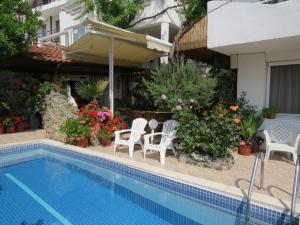 a house with a swimming pool and chairs and flowers at Family Hotel Sofi in Sozopol