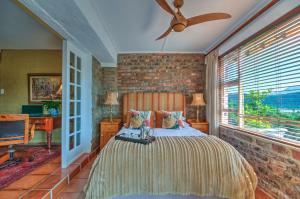a bedroom with a bed and a brick wall at Red Door Cottage in Wilderness
