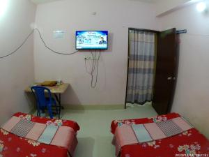 a room with two beds and a television on the wall at Hotel Surma Residential in Dhaka