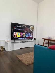 uma sala de estar com uma televisão de ecrã plano num centro de entretenimento branco em Casa Eroilor em Curtea de Argeş
