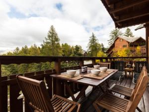 einen Holztisch und Stühle auf einer Terrasse mit Aussicht in der Unterkunft Le chalet Céline in Le Dévoluy