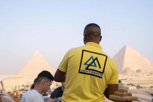 Un homme en chemise jaune qui regarde les pyramides dans l'établissement Great Pyramid Inn, au Caire